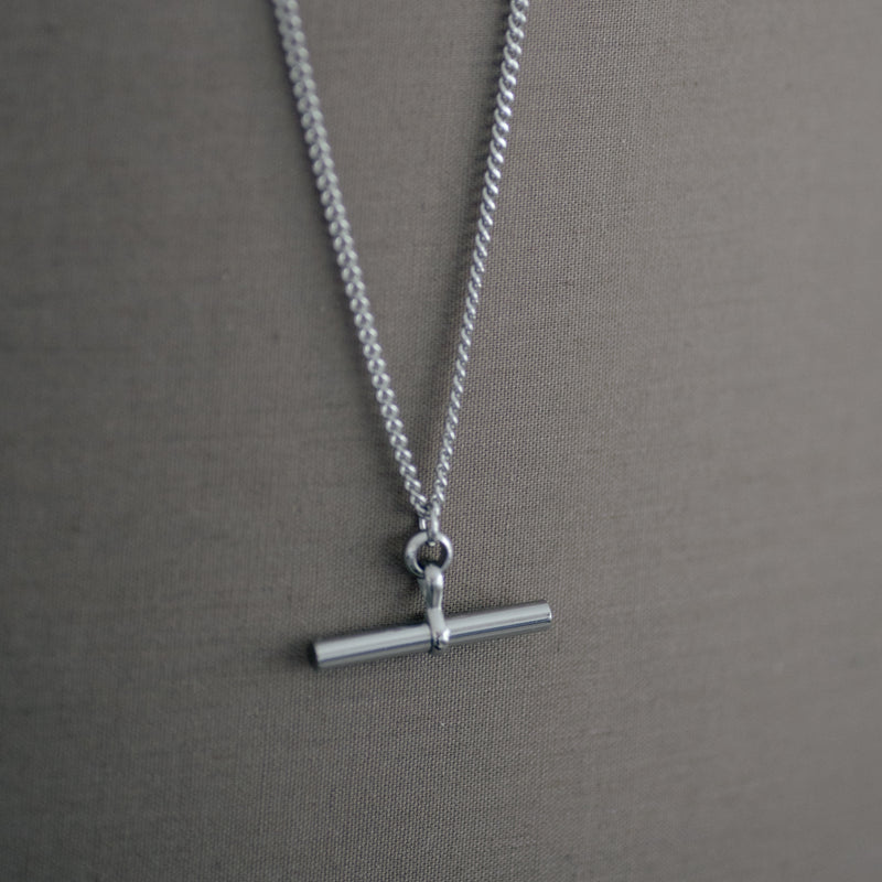 Charlotte 18K gold plated stainless steel necklace with bar pendant on a soft gray background
