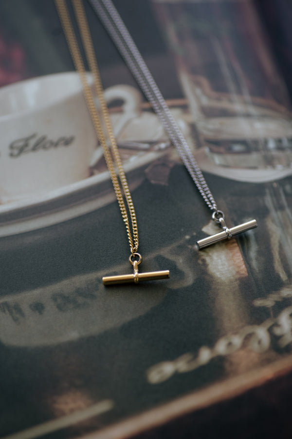 Charlotte 18K gold plated stainless steel necklace with bar pendant on a soft gray background
