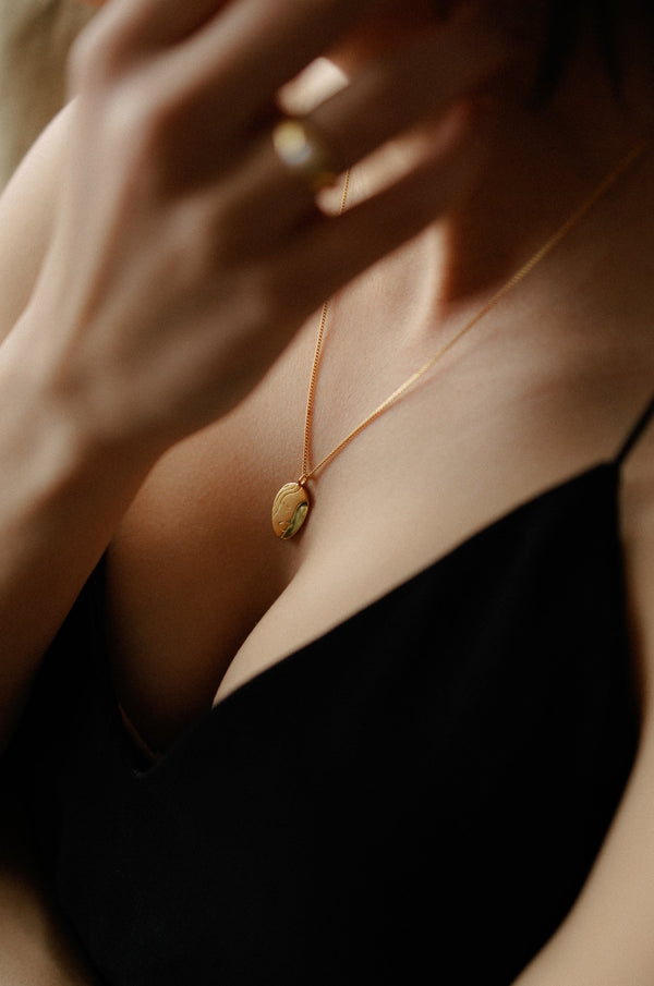 Le Visage 18k gold plated portrait necklace with abstract face design on dark background