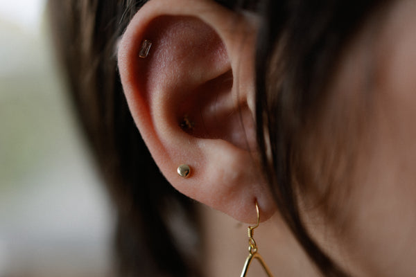 Close-up of Soleil 14K solid gold round stud earrings – minimalist 3mm everyday style