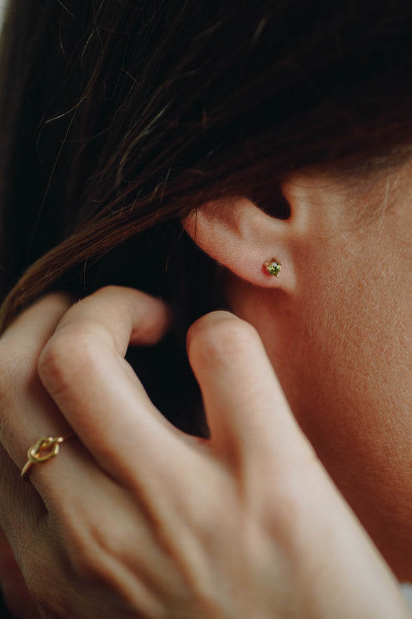 Close-up of Vert d’Eau 14k solid gold stud earrings with green cubic zirconia – minimalist style