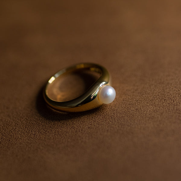 La Perle ring in 18k gold plated brass with pearl accent on brown suede background