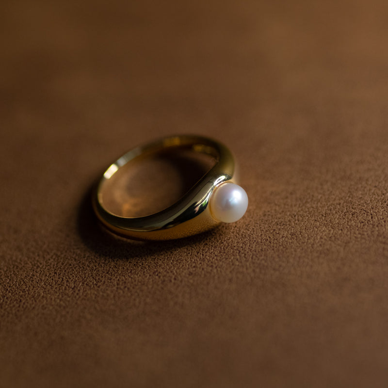 La Perle ring in 18k gold plated brass with pearl accent on brown suede background