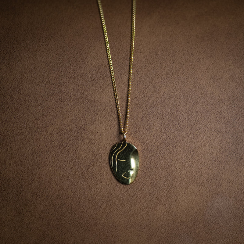 Le Visage 18k gold plated portrait necklace with abstract face design on dark background