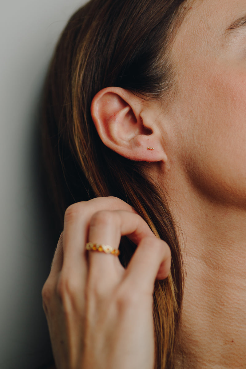 Close-up of Hélène dainty gold bar earrings with secure screw-in back