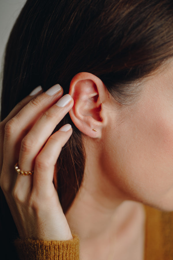 Close-up of Hélène dainty gold bar earrings with secure screw-in back